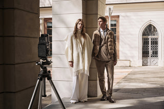 couple in front of vintage photocamera, with white and camel outfits