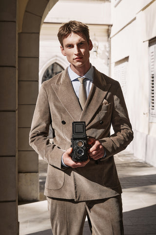 man with elegant camel velvet suit with a vintage camera