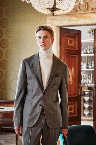 male model with high neck light beige sweater and wool brown suit in an hotel salon