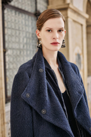 portrait of a woman with silver modern earringgs and a blue elegant coat