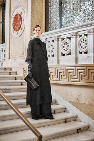 woman with a very elegant black long dress in fil coupé and trousers, with black leather long gloves and cluth bag