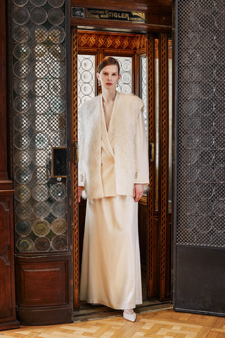 model with a light beige satin blazer and skirt, with an alpaca fil coupé elegant vest inside an ancient elevator