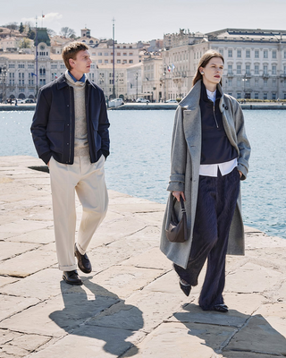 couple wearing grey and blue outfits walking in the historic port and center of Trieste in Italy