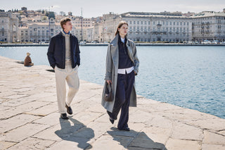 couple wearing grey and blue outfits walking in the historic port and center of Trieste in Italy