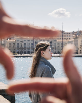 fingers creating a camera shape around the woman walking in trieste