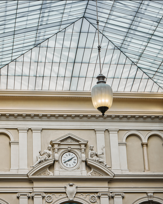 Decorative clock on a building facade with a glass ceiling above